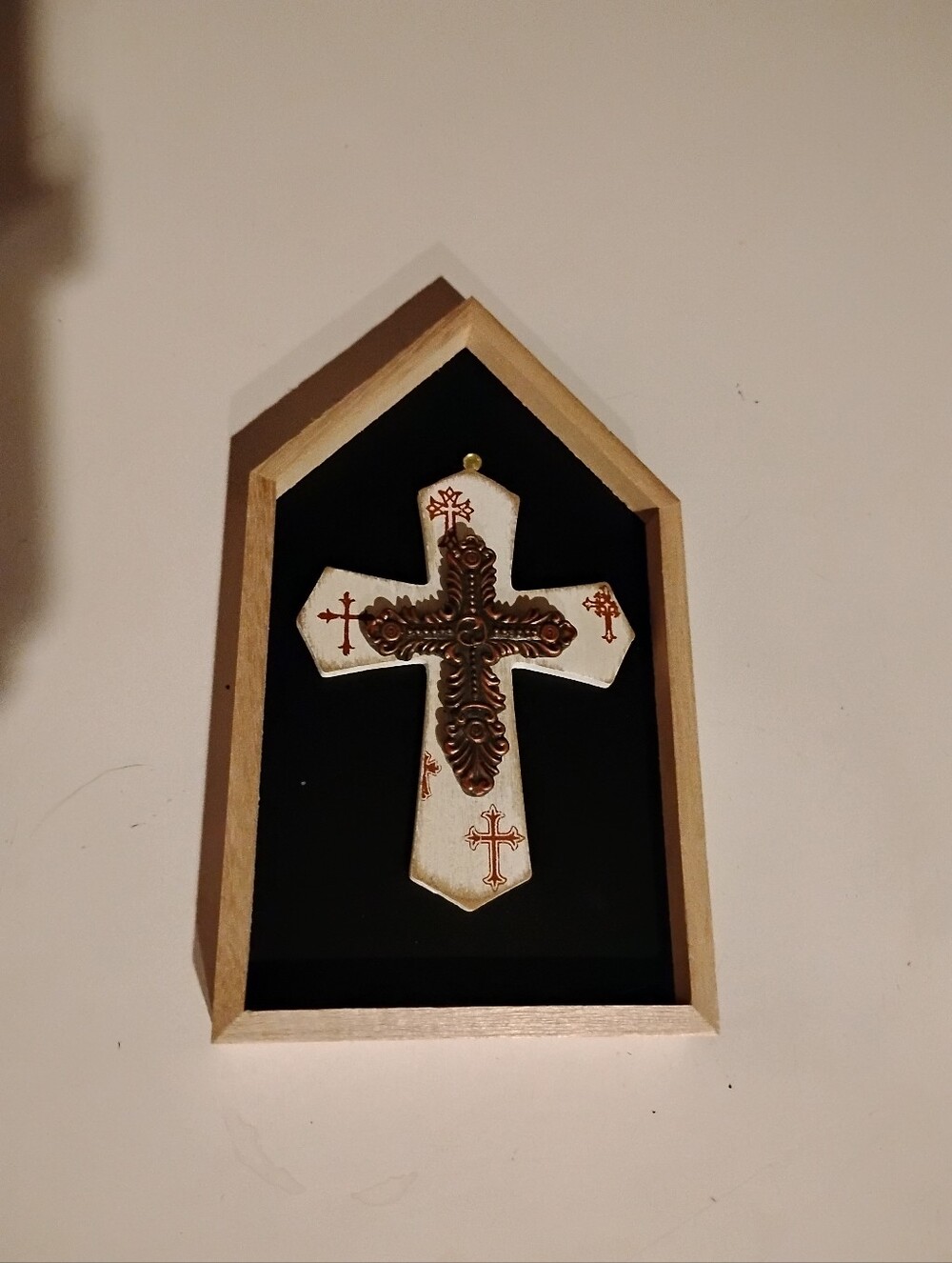 Decorative White Wall Cross with Bronze Accents On The Black In The Wooden Frame